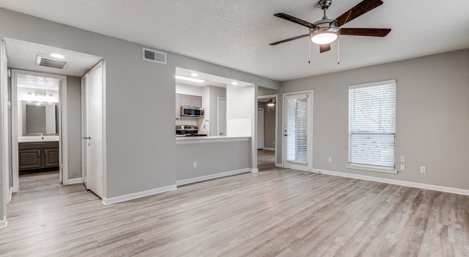 empty living room with ceiling fan and hardwood floors at The Wilder