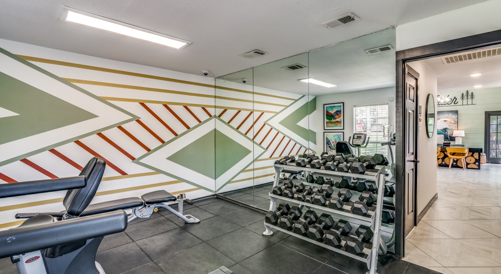 a gym room with weights and a wall of mirrors at The Wilder